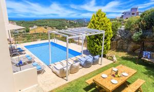 a villa with a swimming pool and a table at Cretan Sunny Villa Heated Pool in Kournás