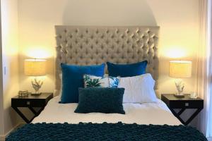 a bedroom with a large bed with blue pillows at Mariner's Cove ~ Luxe Waterfront Apartment in Mindarie