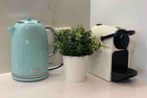 a tea kettle and a potted plant on a counter at Mariner's Cove ~ Luxe Waterfront Apartment in Mindarie