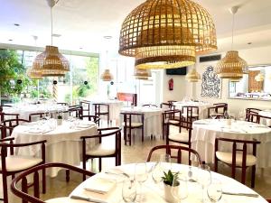 ein Restaurant mit weißen Tischen und Stühlen und Kronleuchtern in der Unterkunft Hotel Calasanz in Molins de Rei