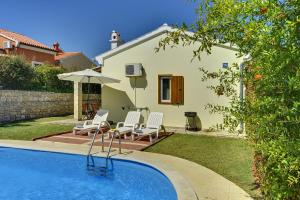 ein Pool mit Stühlen und einem Sonnenschirm und ein Haus in der Unterkunft Villa Helena in Banjole
