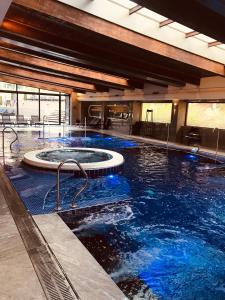 a large swimming pool with blue water in a building at Private Spa Luxury apartments in Bansko