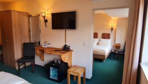 um quarto de hotel com uma secretária, uma cama e uma televisão em Hasseröder Burghotel em Wernigerode