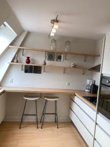 a small kitchen with two bar stools and shelves at Bright apartment in historic City Center in Copenhagen
