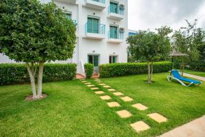 a house with a garden with a blue chair and trees at Résidence Hôtelière Riviera Beach in Cabo Negro