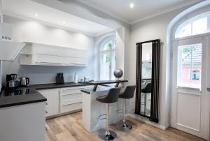eine Küche mit weißen Schränken und einer Theke mit Stühlen in der Unterkunft Wohnperle Apartment Estelle in Dresden