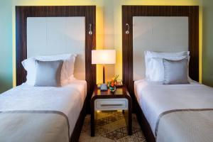 two beds in a room with two lamps at Elite Byblos Hotel in Dubai