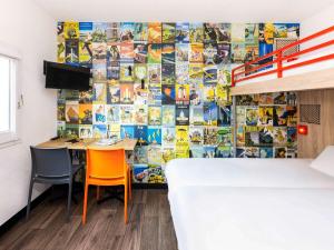 una habitación con una mesa y dos sillas y una pared con carteles en hotelF1 Saint Nazaire La Baule, en Trignac