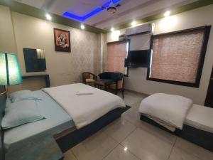 1 dormitorio con 2 camas, silla y ventana en Hotel Geeta Residency Haridwar, en Haridwar