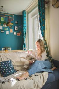 a woman sitting on a bed reading a book at La Kanopee - Les Loges Normandes in Cherbourg en Cotentin