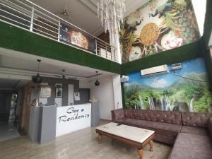 a living room with a couch and a mural at Hotel Geeta Residency Haridwar in Haridwār