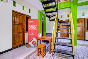 a spiral staircase in a room with a table and a desk at OYO 90636 Happy Syariah in Sleman