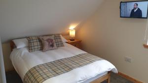 a bedroom with a bed and a tv on the wall at Hebridean Stay in Creagorry