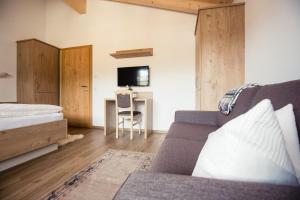 1 dormitorio con sofá, cama y escritorio en Appartemets Hauserbauer en Kaprun