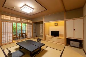 a living room with a table and a television at Ryoso Yufuin Yamadaya in Yufu