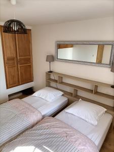 2 camas en una habitación con espejo en PAVILLON DU GARDE CHASSE en Bugnicourt