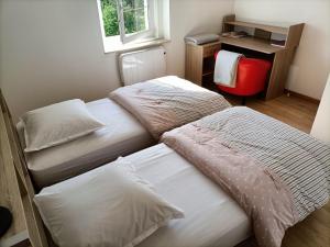 Cette chambre comprend 2 lits dans un bureau et une chaise rouge. dans l'établissement PAVILLON DU GARDE CHASSE, à Bugnicourt