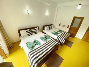two twin beds in a room with yellow floors at Misty Elegance - Ella. in Ella +100 photos