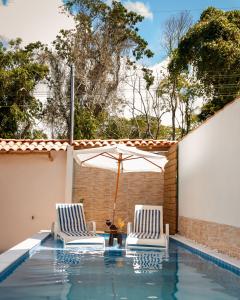 two chairs and an umbrella next to a swimming pool at Casa Viana Trancoso in Trancoso