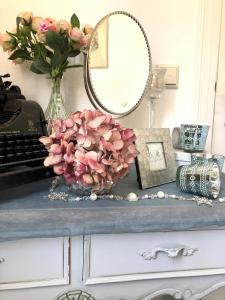 a table with a vase of pink flowers and a mirror at Pension Altstadt Mönch unser Kleinod in top Lage direkt in der Altstadt incl Frühstück in Stralsund
