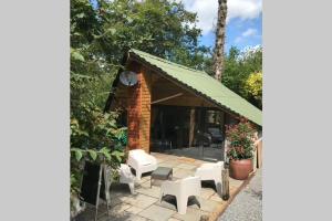 a pavilion with white chairs and a green roof at The Shed . A cosy, peaceful, 96% recycled, chalet. in Swansea