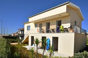 a white house with people sitting on a balcony at Surfivor Surf Camp in Esmoriz