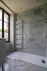 La salle de bains est pourvue d'une douche et d'un mur en marbre. dans l'établissement Manoir de La Croix Saint Louis "Luxury Guest House", à Taingy