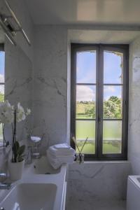 La salle de bains blanche est pourvue d'une fenêtre et d'un lavabo. dans l'établissement Manoir de La Croix Saint Louis "Luxury Guest House", à Taingy