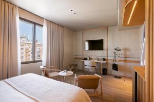 a hotel room with a bed and a table with chairs at Only YOU Hotel Málaga in Málaga