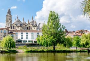 um grande edifício branco com uma árvore em frente a um rio em ibis Périgueux Centre em Périgueux