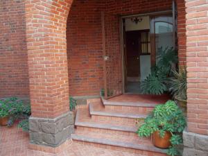 wejście do ceglanego budynku ze schodami i roślinami w obiekcie Hostal La Encantada w mieście Meksyk