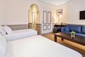
a hotel room with a couch, coffee table and a television at H10 Corregidor Boutique Hotel in Seville
