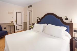 a bedroom with a large white bed with a blue headboard at H10 Corregidor Boutique Hotel in Seville