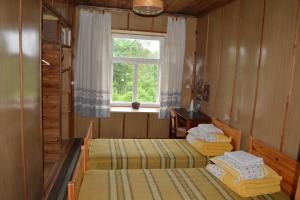 two beds in a room with a window at Lauku sēta Svētupes in Salacgrīva