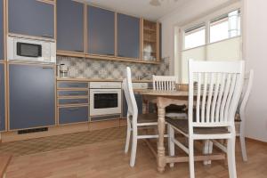 ヴィーク・アウフ・フェールにあるHaus Poggfred Whg 02 Arfstenのキッチン(青いキャビネット、テーブル、椅子付)