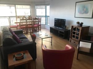 sala de estar con sofá, TV y sillas en Departamento en Condominio Puerto Pacífico, en Viña del Mar