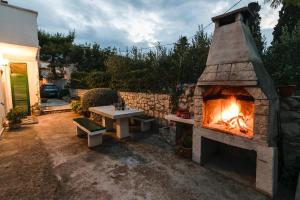 a stone fireplace with two benches and a table at Apartment Dunja in Supetar