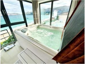 a bath tub in a room with a view of the ocean at Apartments Toni in Baška