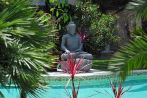 a statue sitting next to a pool in a garden at Villa Valflor chambres d'hôtes et appartements in Marseille