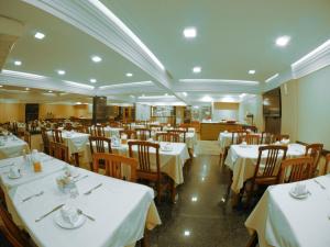 uma sala de jantar com mesas brancas e cadeiras com toalhas de mesa brancas em Icaraí Praia Hotel em Niterói