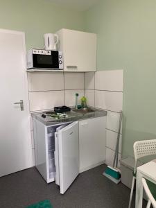 a kitchen with a stove, microwave, and refrigerator at Ullis Pension für Monteure & Handwerker in Malsch