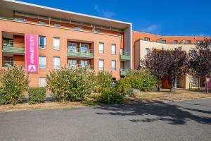 een gebouw met een roze bord ervoor bij Appart'City Confort St Quentin en Yvelines - Bois D'Arcy in Bois-dʼArcy