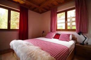 a bedroom with a bed with red curtains and windows at Haus Waldruhe in Mallnitz