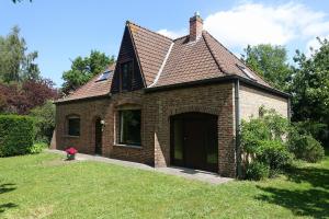 a brick house with a large door in the grass at Lien's Cottage in Bruges