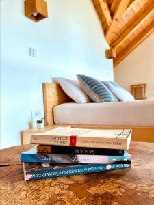 a stack of books sitting on a table next to a bed at Planinska Koliba Exclusive in Sekulić 