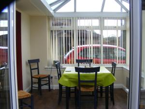 ein Esszimmer mit Tisch und Stühlen und einem Fenster in der Unterkunft Dingieshowe Cottage in Lennoxtown