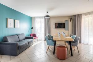 a living room with a couch and a table and chairs at Appart'City Confort St Quentin en Yvelines - Bois D'Arcy in Bois-dʼArcy