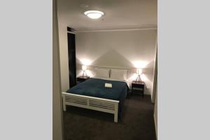 a bedroom with a bed with a blue blanket and two lamps at Liverpool holiday apartment 2Bedroom 2Bathroom in Liverpool