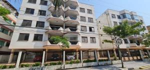 un grand bâtiment blanc avec des fenêtres et des arbres dans l'établissement Ap da Mama, à Guarujá