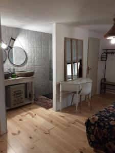 een badkamer met een wastafel, een bureau en een spiegel bij chambre k au domaine du mont scolan in Montgardon